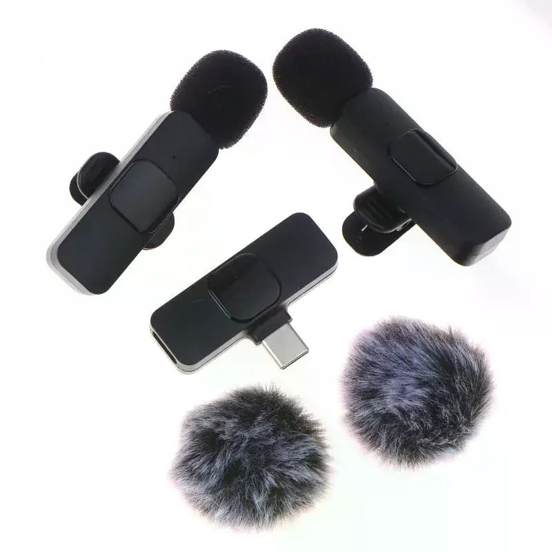 Two black clip-on USB microphones with furry windshields, a matching USB-C receiver dongle, and two detachable gray-and-black furry microphones, arranged on a plain white background.