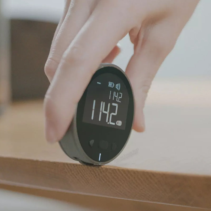 Smart Digital Measuring Tape with LCD Display held by a hand with a blurred background