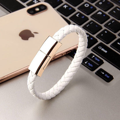 White braided Wearable smartphone charging cable braceletwith gold clasp on a laptop keyboard