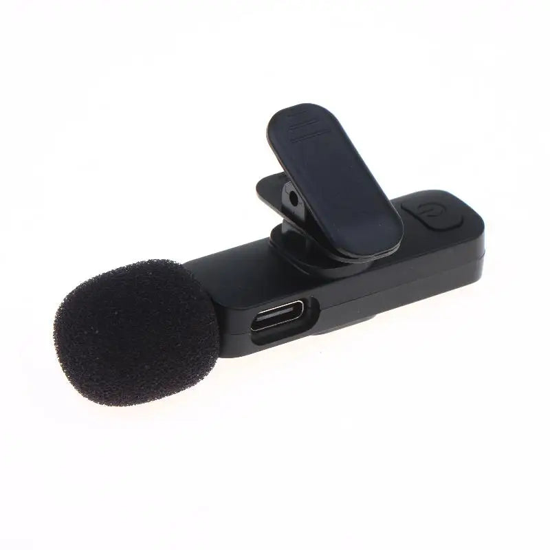 A black clip-on wireless microphone with a foam windscreen and a USB-C port, shown on a plain white background.