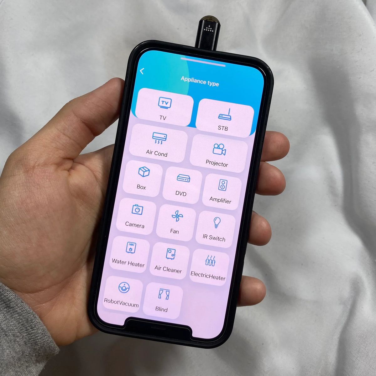 Hand holding a smartphone with an app interface Smartphone infrared remote control adapter